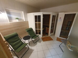 Une pièce avec deux chaises vertes, une petite table ronde, une porte coulissante et un sol carrelé.