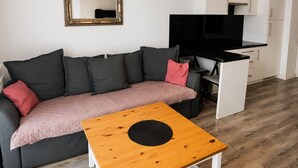 Uma sala de estar moderna com sofá, mesa de centro, televisão e área de cozinha.
