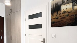 Um corredor com uma porta branca, um guarda-roupa de madeira e um quadro de uma casa na parede.