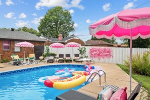 En baghave med swimmingpool, oppustelige poollegetøj og udendørs møbler.