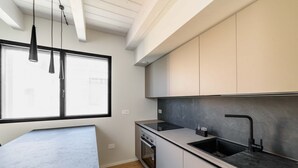 Eine moderne Küche mit großem Fenster, Einbauofen und einer schwarzen Arbeitsplatte.