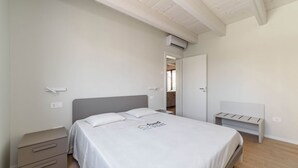 Ein Schlafzimmer mit Bett, Nachttischen, einem Kleiderschrank und einer Klimaanlage.