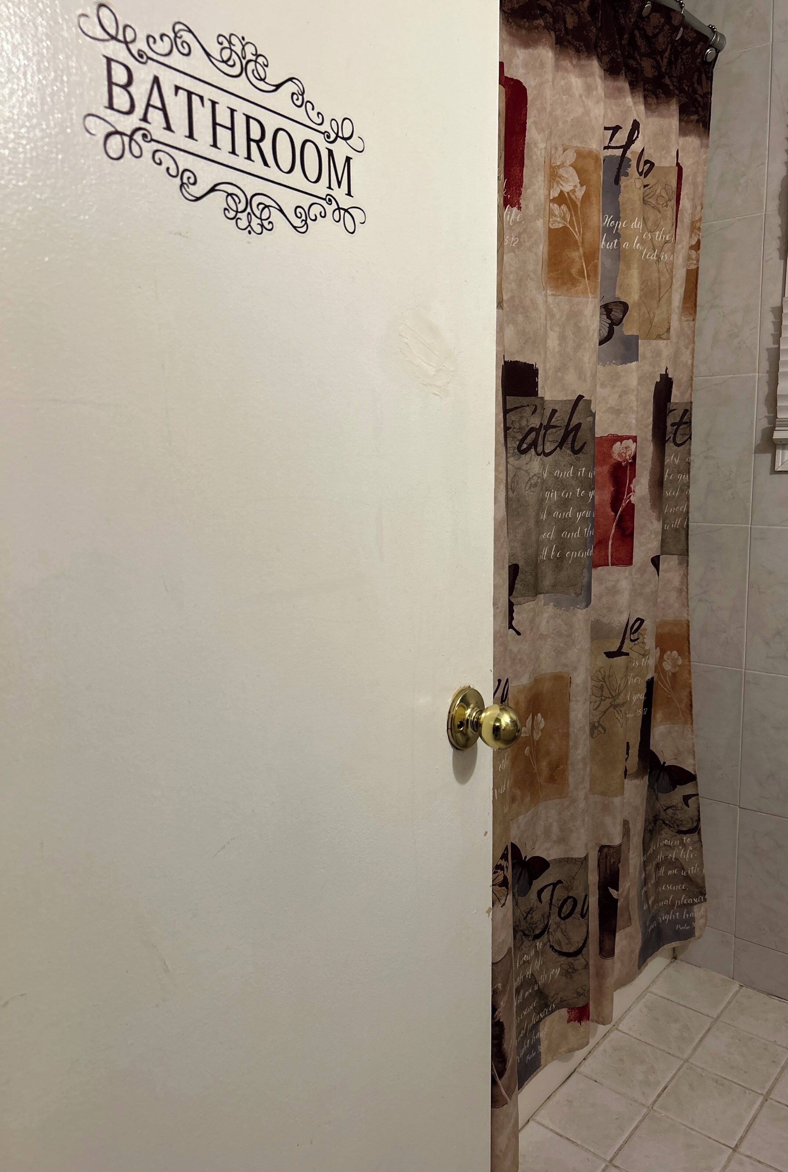 A bathroom with a door labeled 'BATHROOM' and a curtain with various text and images.