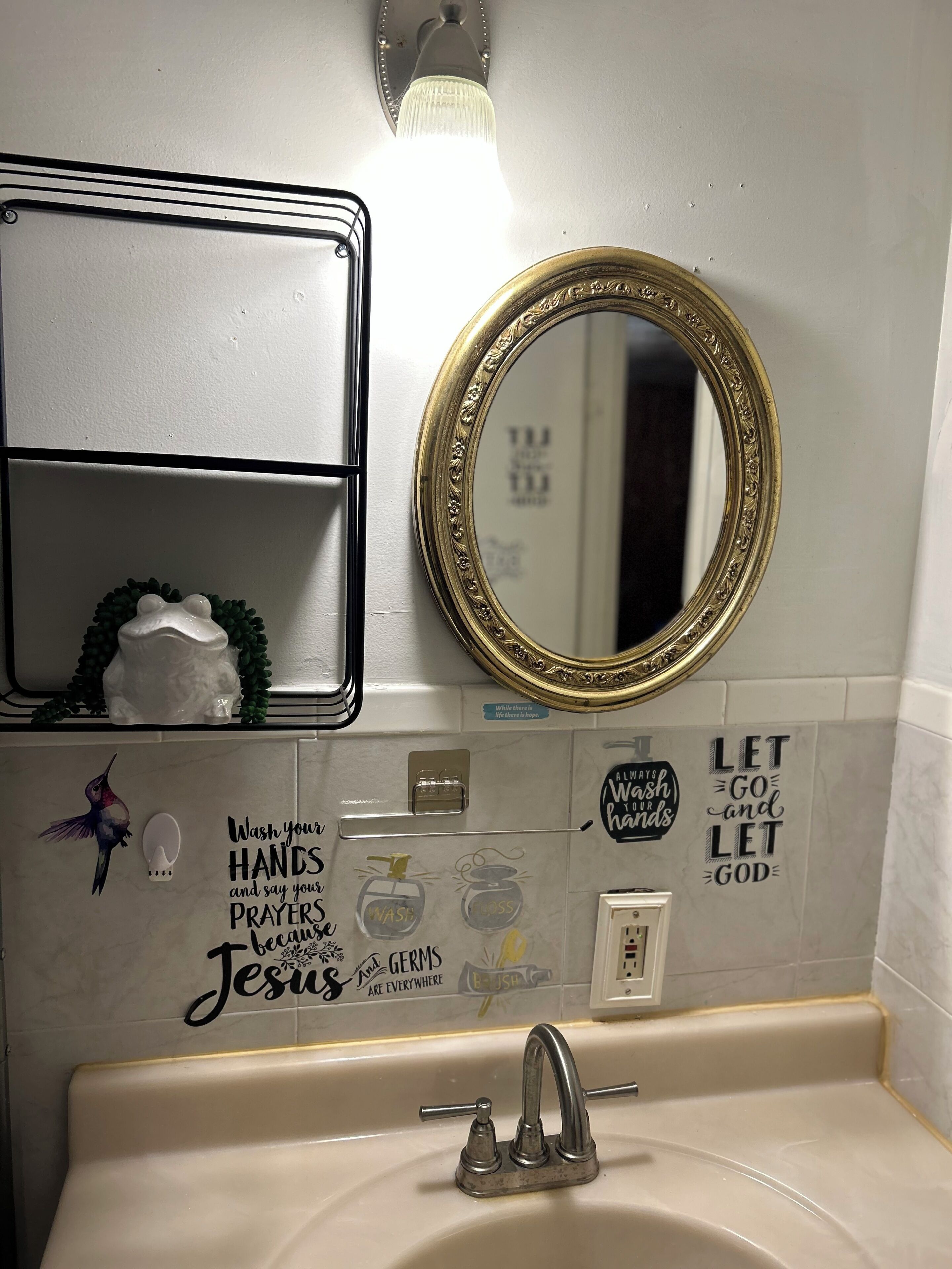 A bathroom with a sink, mirror, and decorative wall stickers.