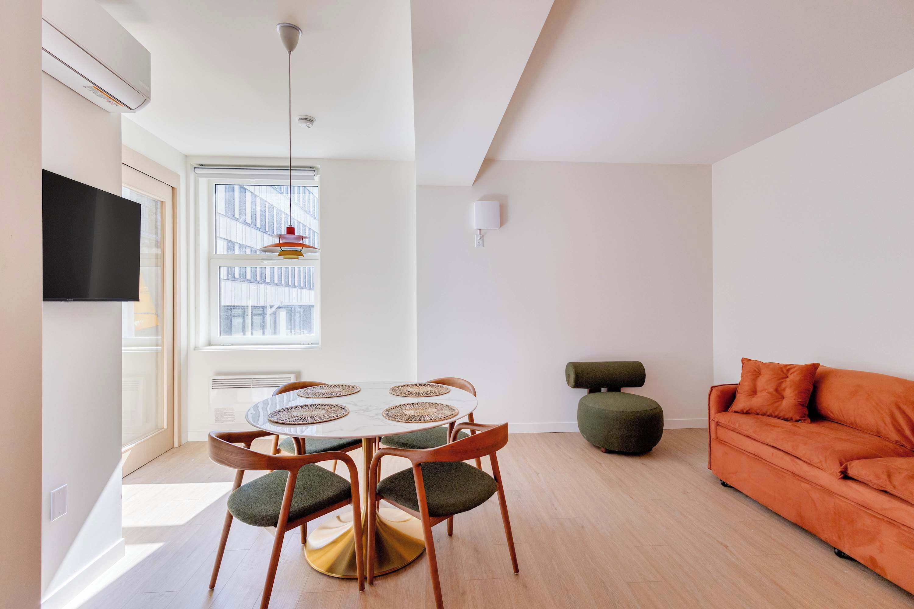 A modern living space with a dining area, a sofa, and a television.