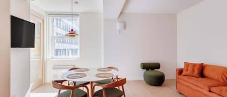 A modern living space with a dining area, a sofa, and a television.