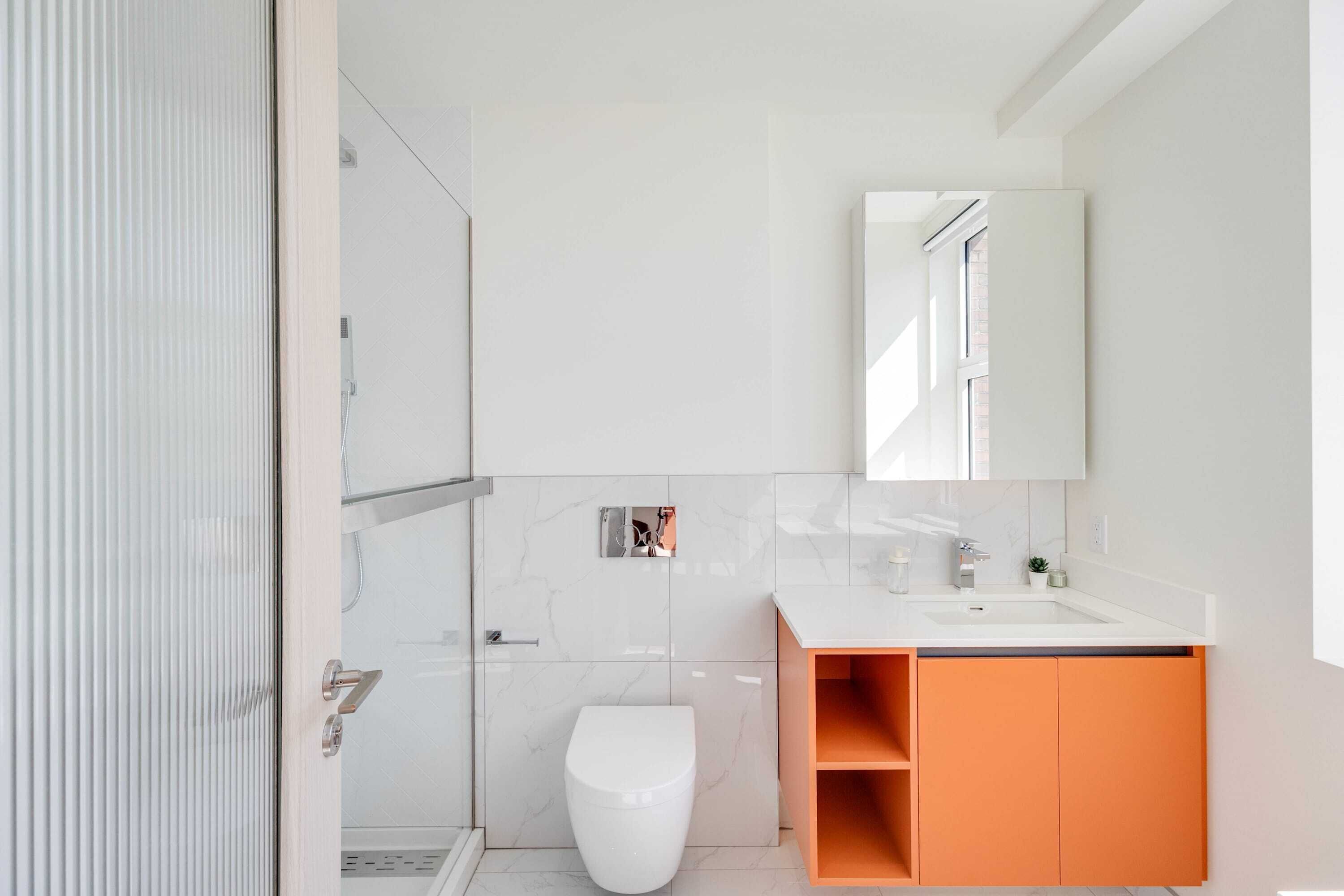 A modern bathroom with a toilet, sink, and mirror.
