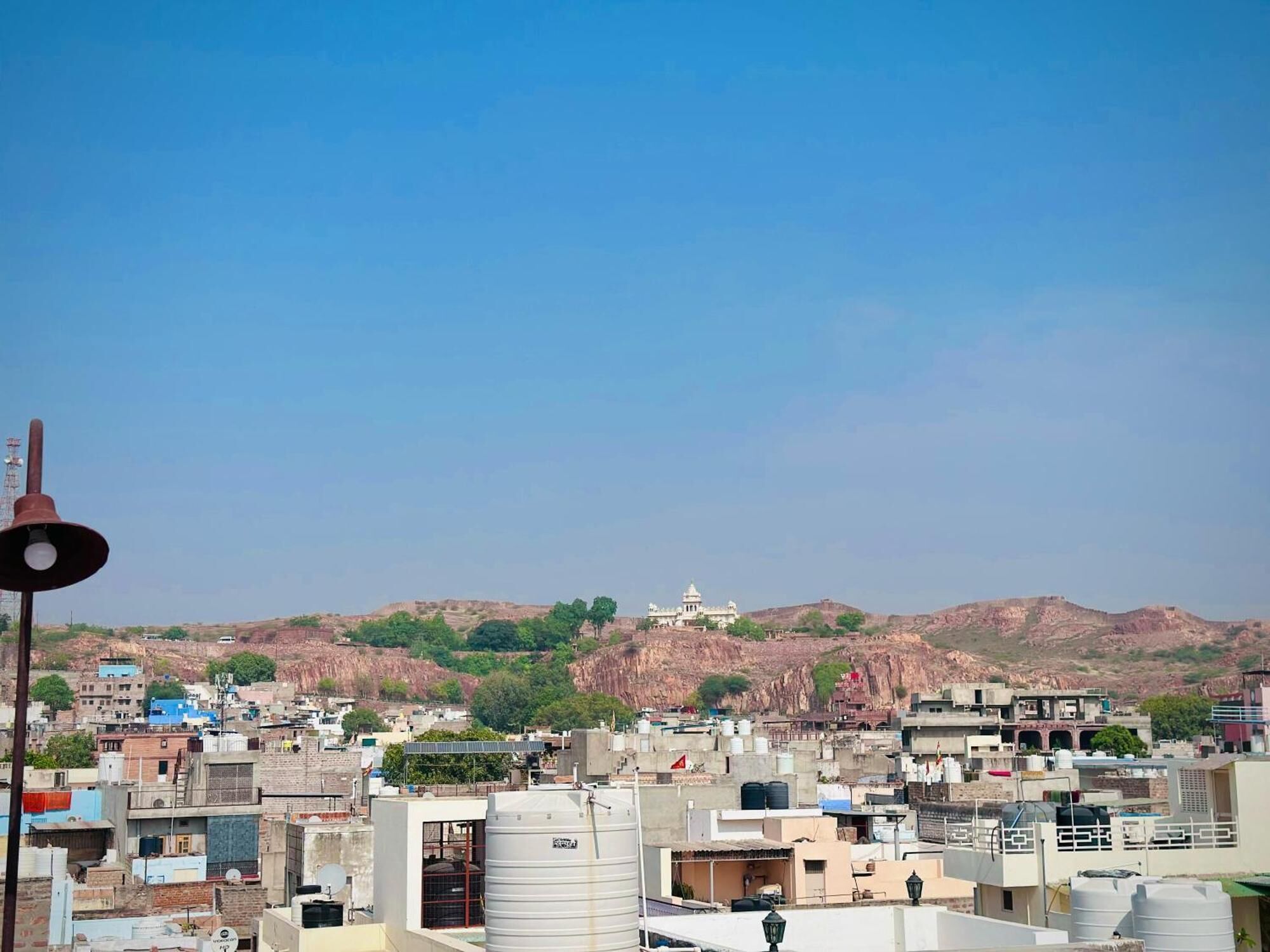 A cityscape with buildings, a water tower, and a hill with a structure on top.