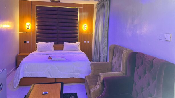 Habitación de hotel con una cama grande, un sofá, una lámpara de techo y lámparas de pared.