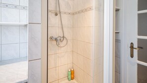 A bathroom with a shower, tiled walls, and a door with a handle.