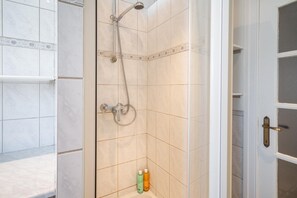 A bathroom with a shower, tiled walls, and a door with a handle. - Elegant 3bhk Apart With Modern Amenities (Antwerp)