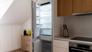 Eine kleine Küche mit integriertem Kühlschrank, einer Mikrowelle und einem Herd.