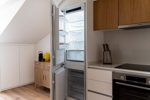 Eine kleine Küche mit integriertem Kühlschrank, einer Mikrowelle und einem Herd.