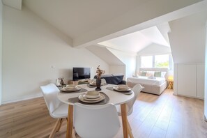 Ein moderner, offener Wohnbereich mit Essplatz, Fernseher und Sofa.