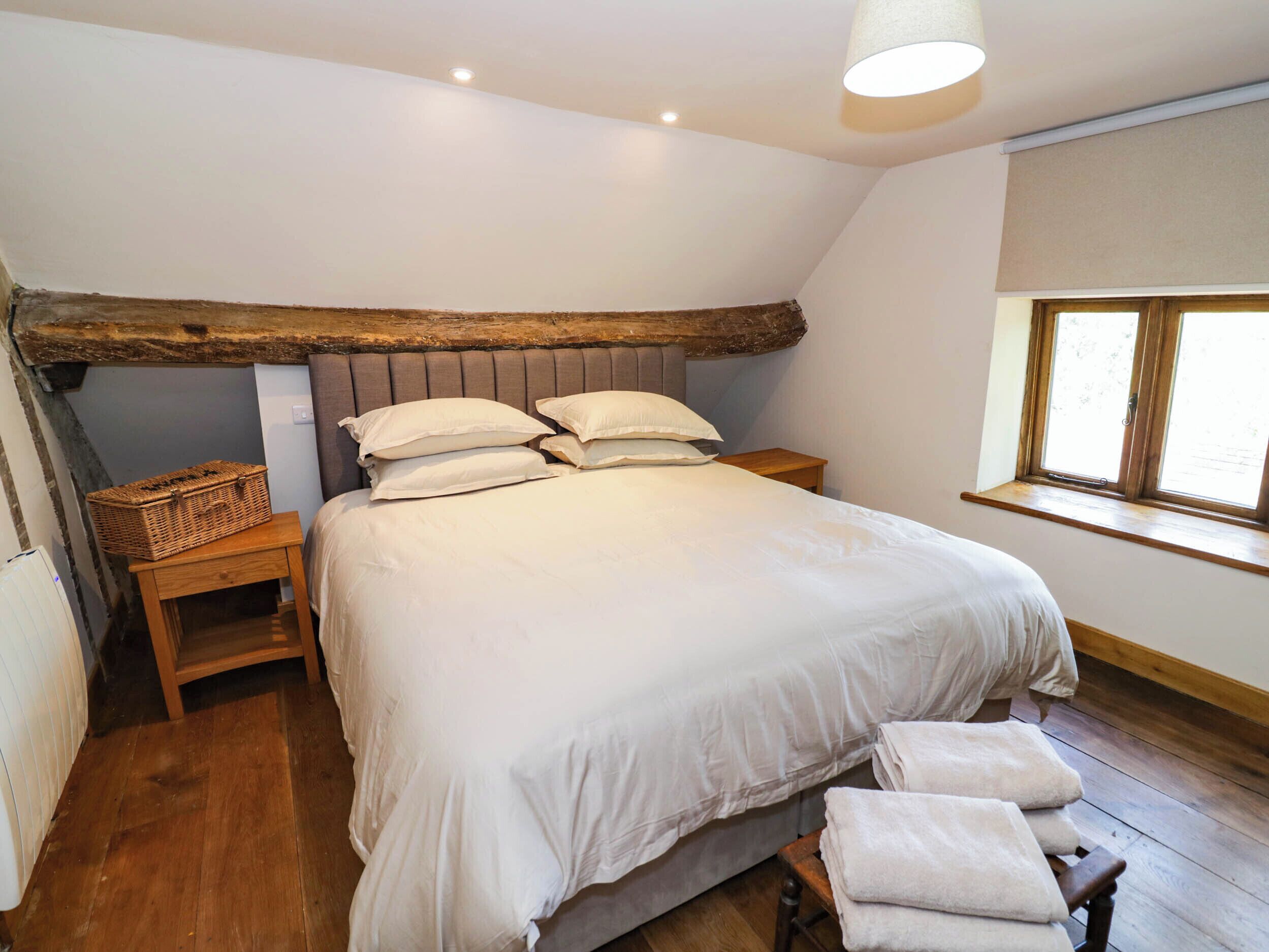 A bedroom with a large bed, wooden headboard, bedside tables, a window with a view, and a ceiling light.