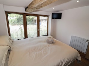 Ein Schlafzimmer mit einem großen Bett, einem an der Wand montierten Fernseher und einer Heizung.