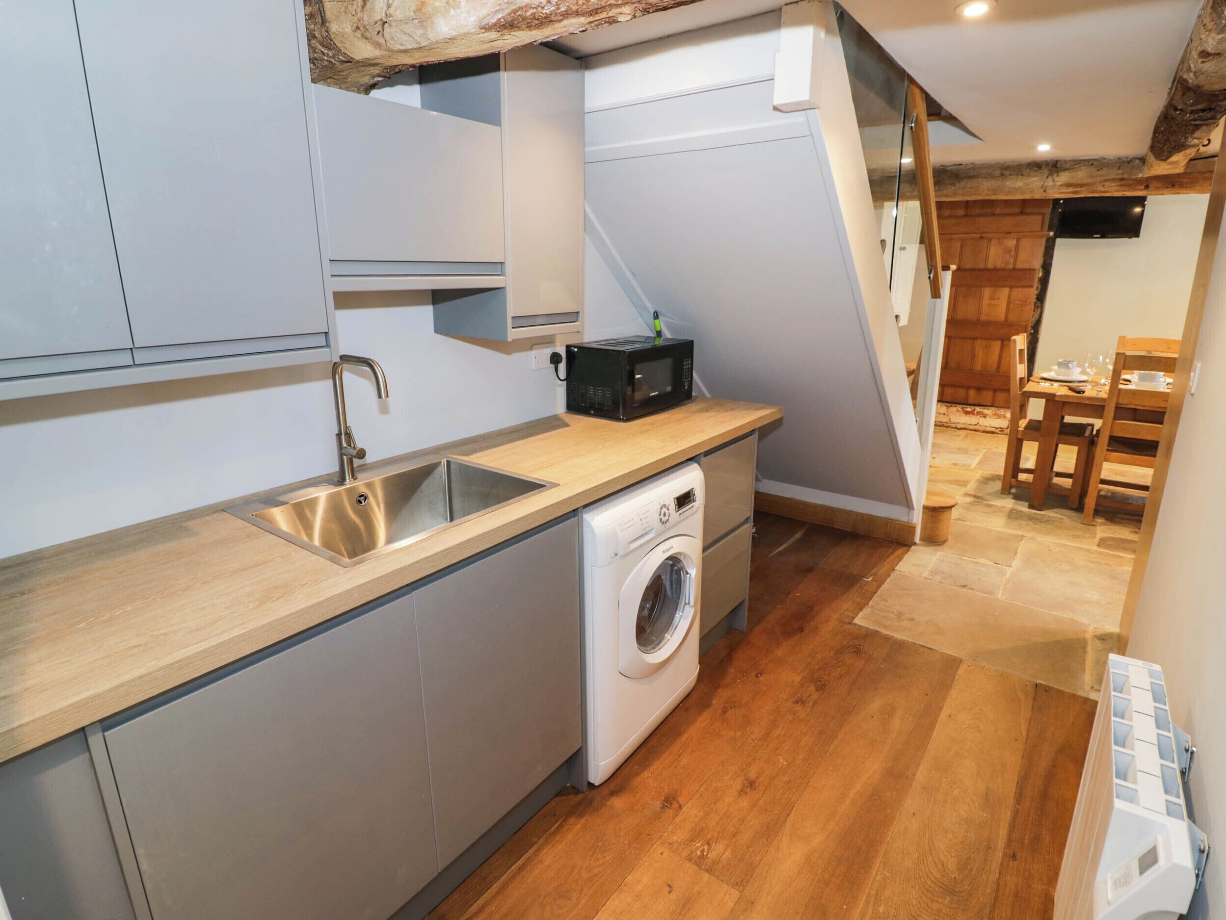 A compact kitchen with a washing machine, a sink, and a microwave.