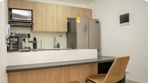 Una cocina moderna con isla integrada, electrodomésticos de acero inoxidable y un espacio de asiento con dos taburetes y una silla.