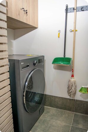 A laundry area with a washing machine, a mop, and a broom. - Luxury Apt w/Balcony-Stunning View near el Tesoro (Medellín)
