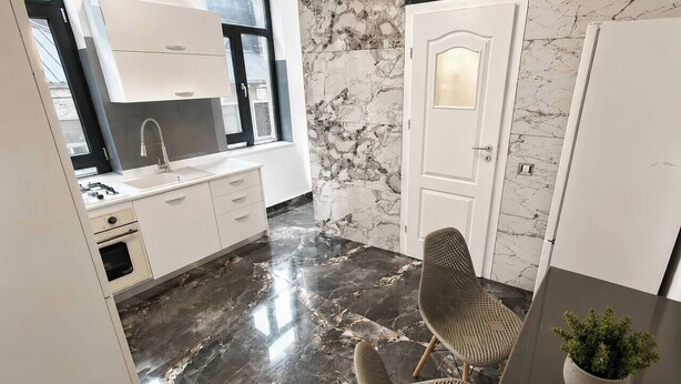 Een moderne keuken met een marmeren achterwand, een ingebouwde oven en een eethoek met een tafel en stoelen.