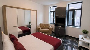 Een hotelkamer met een bed, een stoel, een kledingkast, een televisie en een raam.