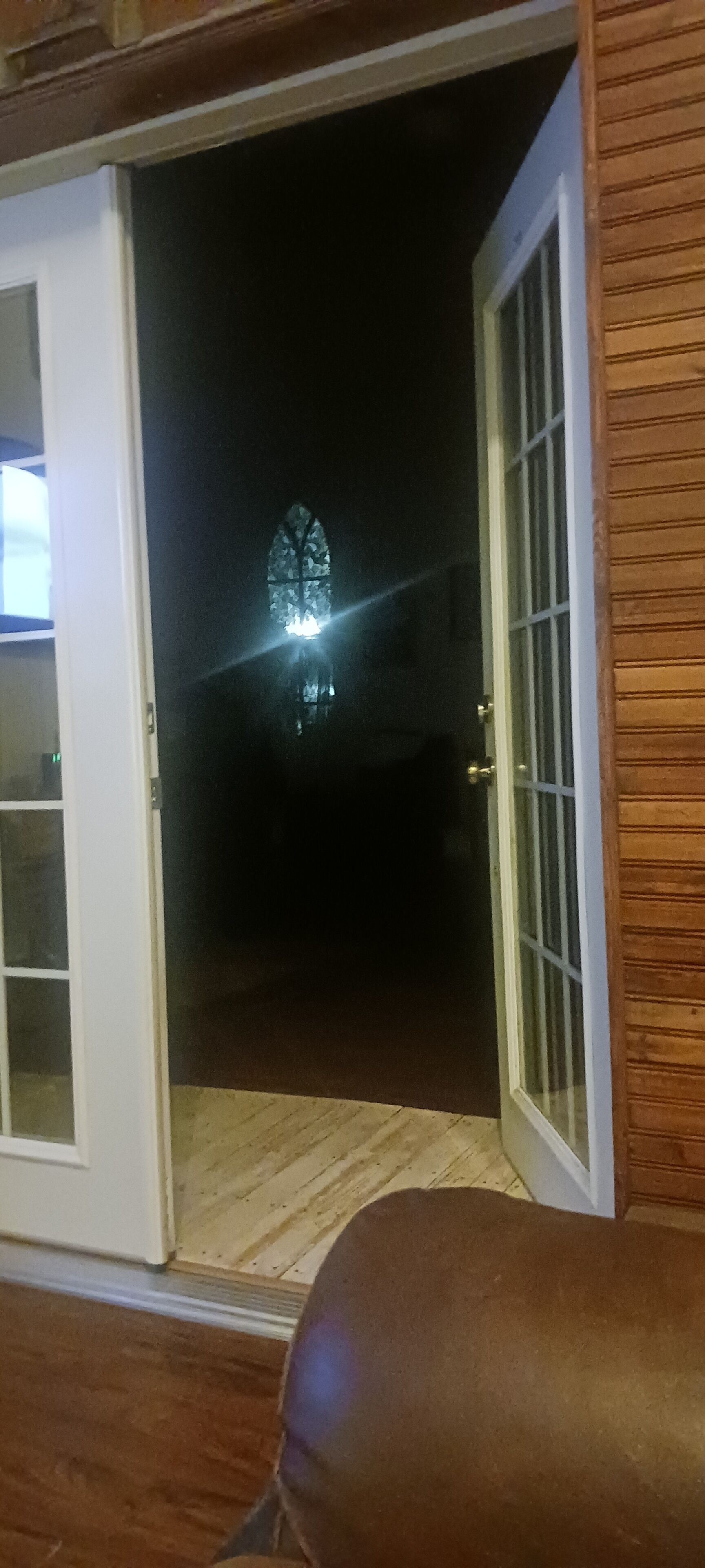 Une porte ouverte donnant sur un intérieur sombre, avec une fenêtre visible.