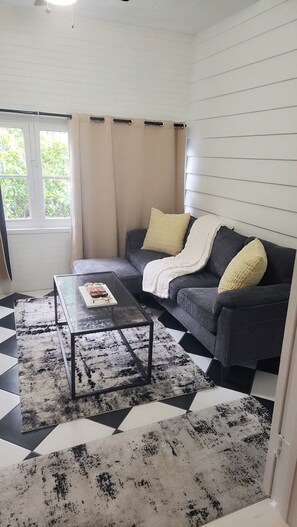 A living room with a sofa, a coffee table, and a patterned rug. - ​Charming Historic Cozy Getaway • Free Parking! • Walkable to Everything (St. Augustine)
