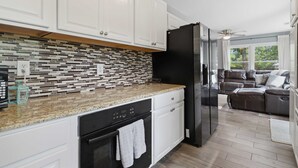 A modern kitchen with white cabinets, a black refrigerator, and a tiled backsplash. - Lakefront Home 3 Bedroom 2 Bath With Private Dock (Gravois Mills)