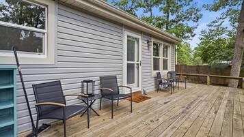 A covered deck with outdoor furniture, a wooden fence, and a house with large windows.