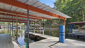 A dock with a covered area, a boat, and a water body. - Lakefront Home 3 Bedroom 2 Bath With Private Dock (Gravois Mills)