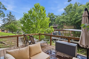 A wooden deck with a sofa, chairs, and a covered area with an umbrella.
