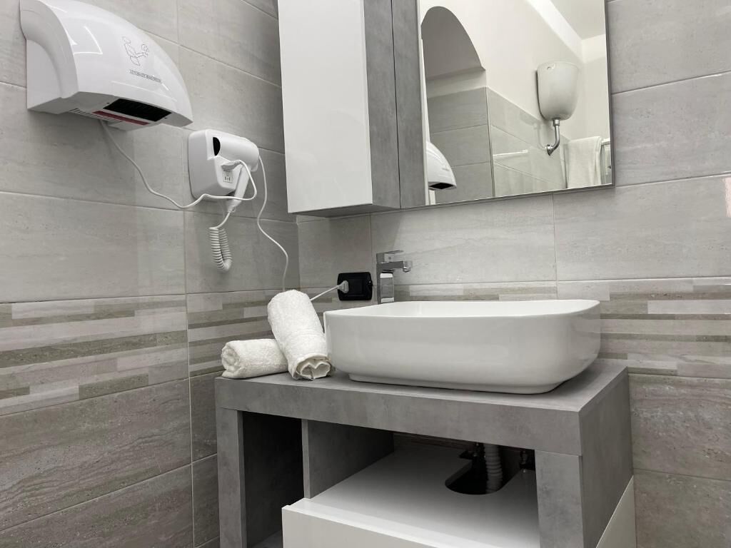 A modern bathroom with a large sink, a towel dispenser, and a mirror.