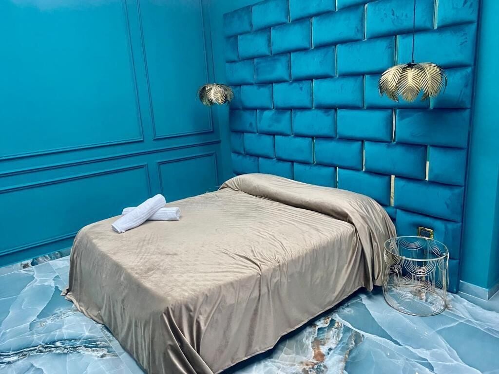 A room with a bed, a blue wall, and a patterned floor.