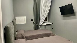 Una habitación con dos camas, un televisor instalado en la pared y un equipo de aire acondicionado.