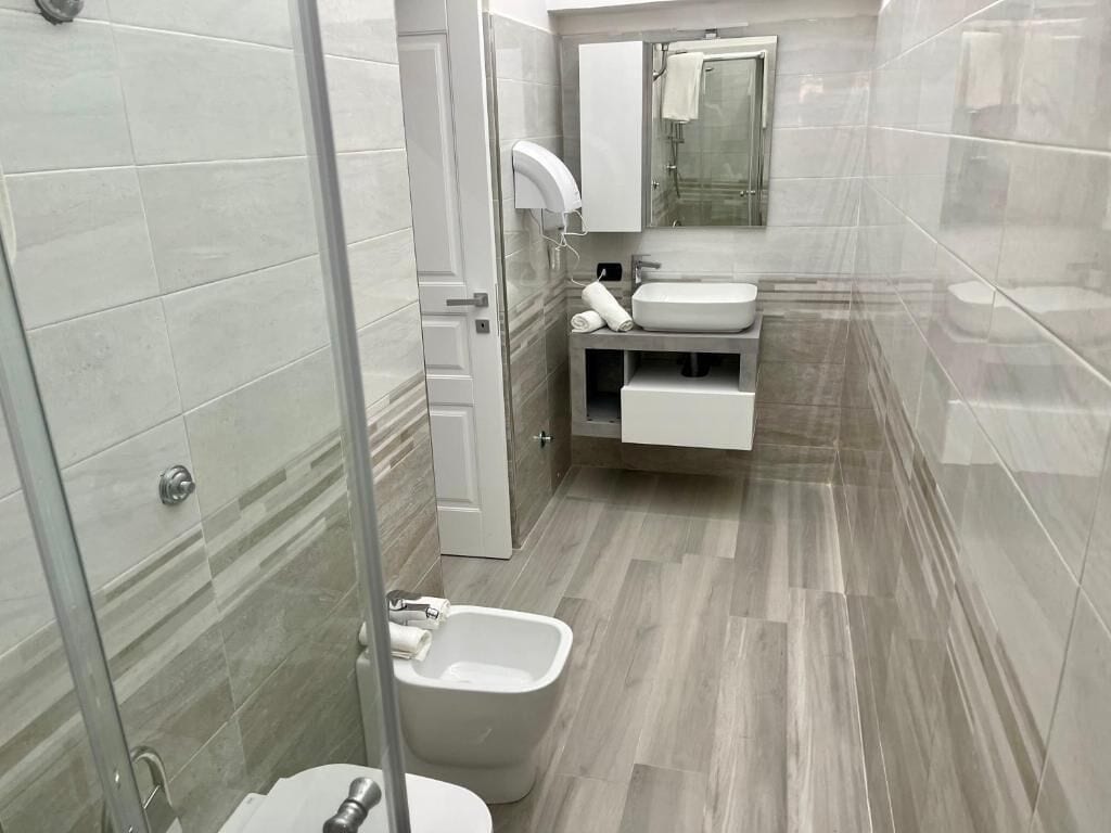 Un bagno moderno con cabina doccia in vetro, lavandino bianco e servizi igienici.