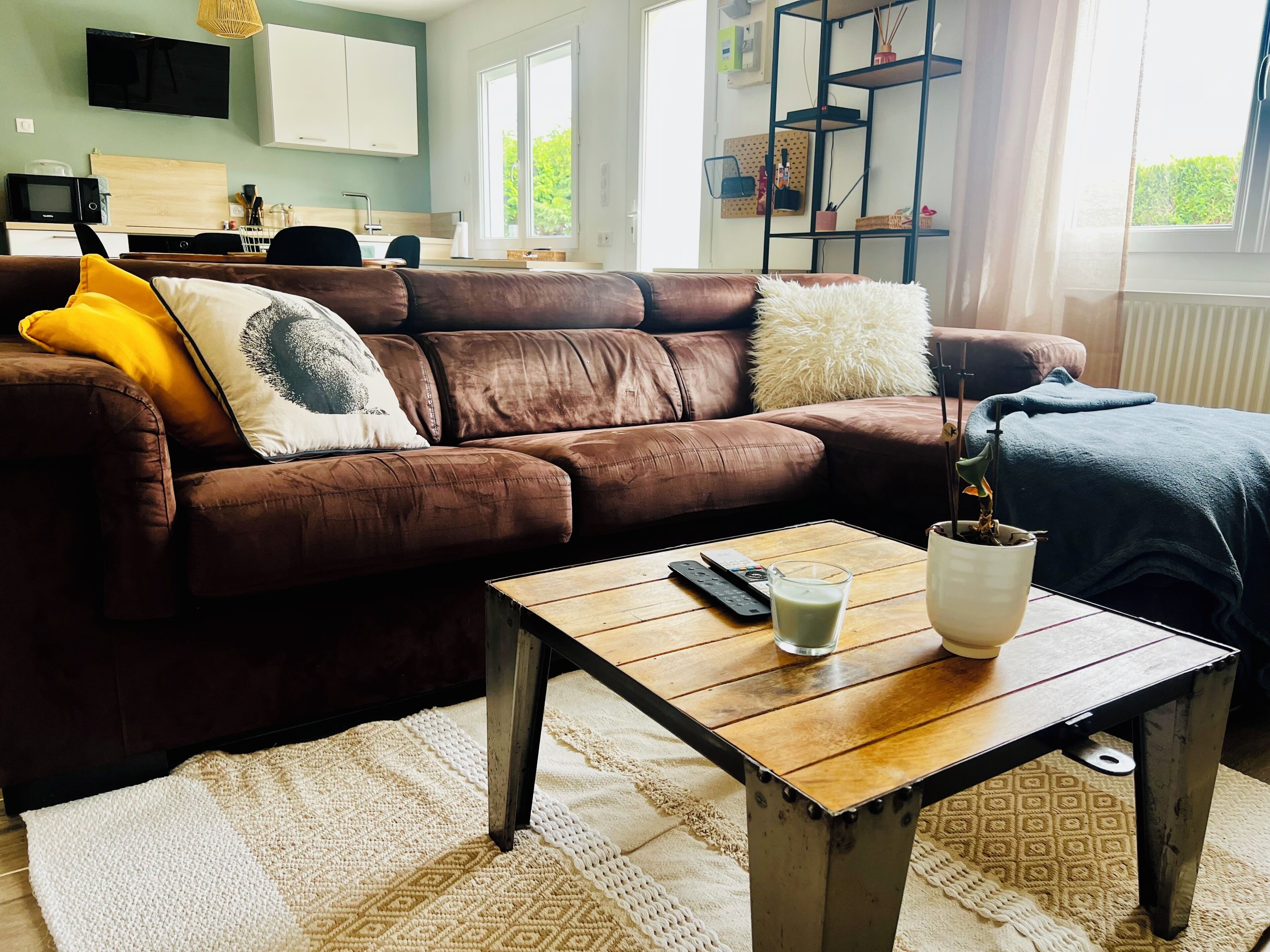 A living room with a brown leather sofa, a wooden coffee table, and a remote control.