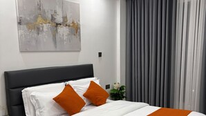 A modern hotel room with a large bed, a nightstand, a wall-mounted artwork, and a window with curtains. - Modern 1-Bedroom in Kilimani  Pool, Gym, Fast Wi-Fi, Near Yaya & CBD (Nairobi)