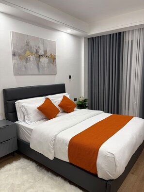 Ein modernes Hotelzimmer mit einem großen Bett, einem Nachttisch, einem Wandbild und einem Fenster mit Vorhängen.