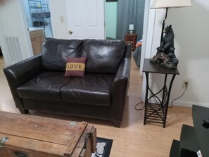 A living room with a leather sofa, a wooden coffee table, and a bear statue on a side table. - Black Bear Ridge  (Bryson City)
