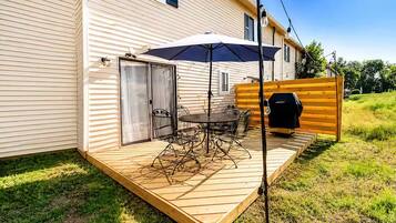 A patio with a table and chairs, a grill, and a covered area with an umbrella.