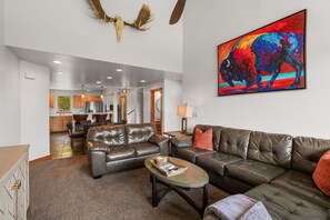 Ein geräumiges Wohnzimmer mit Ledersofas, einem Couchtisch und einem lebhaften, abstrakten Gemälde.