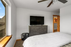 A bedroom with a bed, a dresser, a television on the wall, a ceiling fan, and a window. - Big Sky Escape! 5 minute walk from Town Center! (Big Sky)