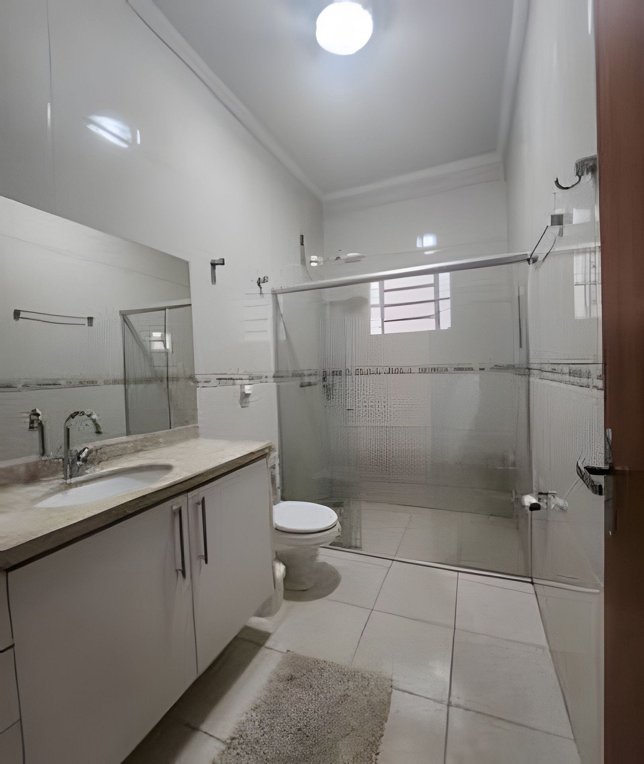 Un baño moderno con cabina de ducha de vidrio, inodoro y lavabo con espejo sobre él.