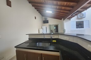 A kitchen with a black countertop, wooden cabinets, and a ceiling with exposed beams.