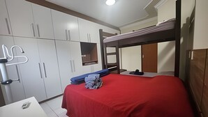 Een slaapkamer met een stapelbed, een garderobe en een bureau met een stoel.