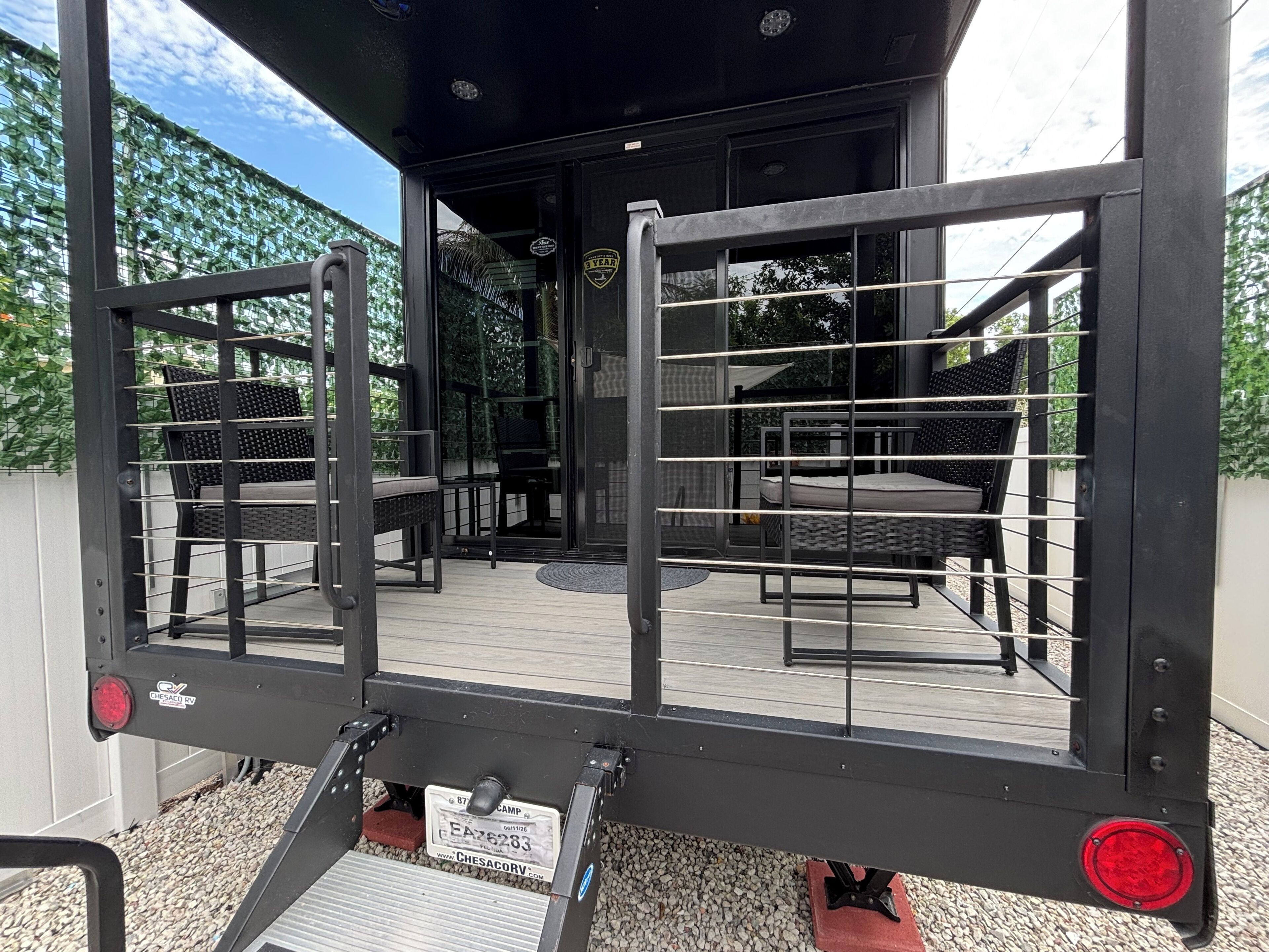 A metal gate with a label, a patio area with a table and chairs, and a view of the outdoors.