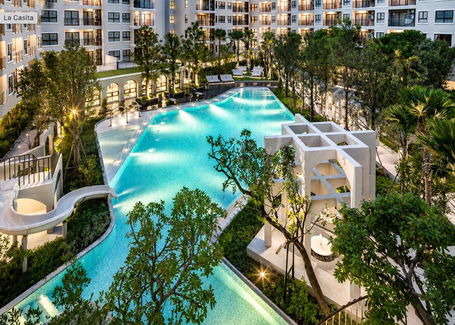 A resort with a large swimming pool, multiple balconies, and lush landscaping.