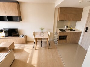 A compact living space with a kitchenette, a dining area, and a television on a wooden console. - La Casita Hua Hin Premium Stay with Playstation (Tambon Hua Hin)