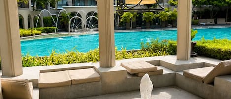 A poolside area with a fountain, seating, and a view of a hotel building.