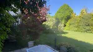 An outdoor patio with a table and chairs, surrounded by greenery and trees. - Bed and Breakfast 'Sous Les Bruyères' with Private Terrace, Private Garden and Wi-Fi (Sainte-Marguerite-sur-Mer)